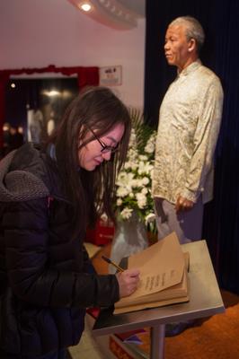 游客在上海杜莎夫人蠟像館曼德拉蠟像邊的吊唁本上寫下唁詞，寄托哀思